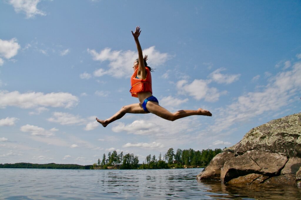 woman jumping towards water wearing life vest